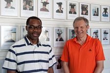 Foto von Christophe Bobda und Prof. Teich vor einer Wand mit Bildern von Absolventen