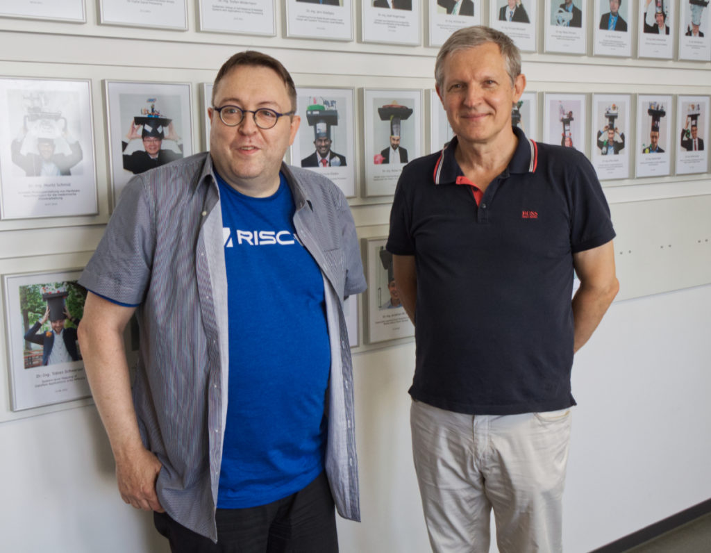 Zwei Personen vor einer Wand mit Bildern